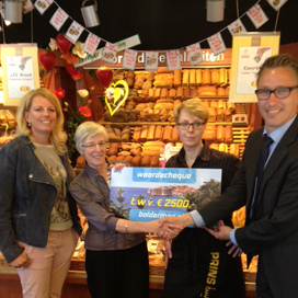 De uitreiking van de reischeque in de winkel van ondernemers Joost en Claudia Prins (links op de foto) in Dronten.