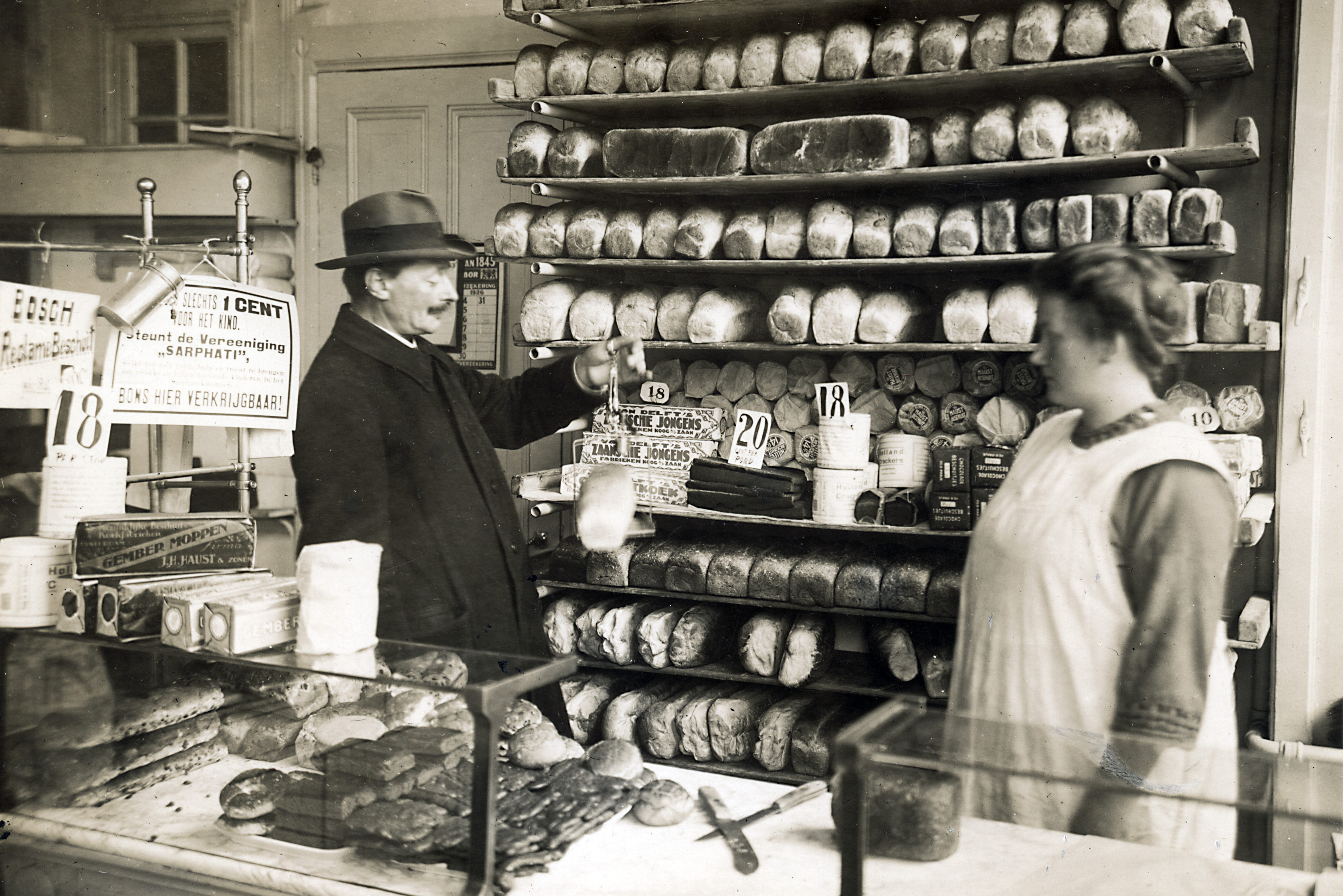 Een ambtenaar van de Keuringsdienst van Waren keurt een brood door het te wegen met een handweegschaaltje. 
Foto: Maria Austria / HH