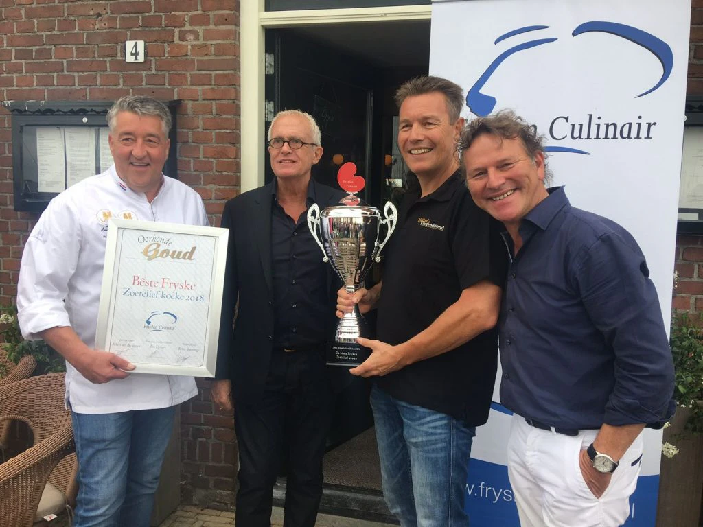 De winnaar kreeg de bokaal uitgereikt door de partner van de eind 2016 overleden Joop Braakhekke, Wim Nijkamp, en juryvoorzitter Robèrt van Beckhoven. Foto: Fryslân Culinair