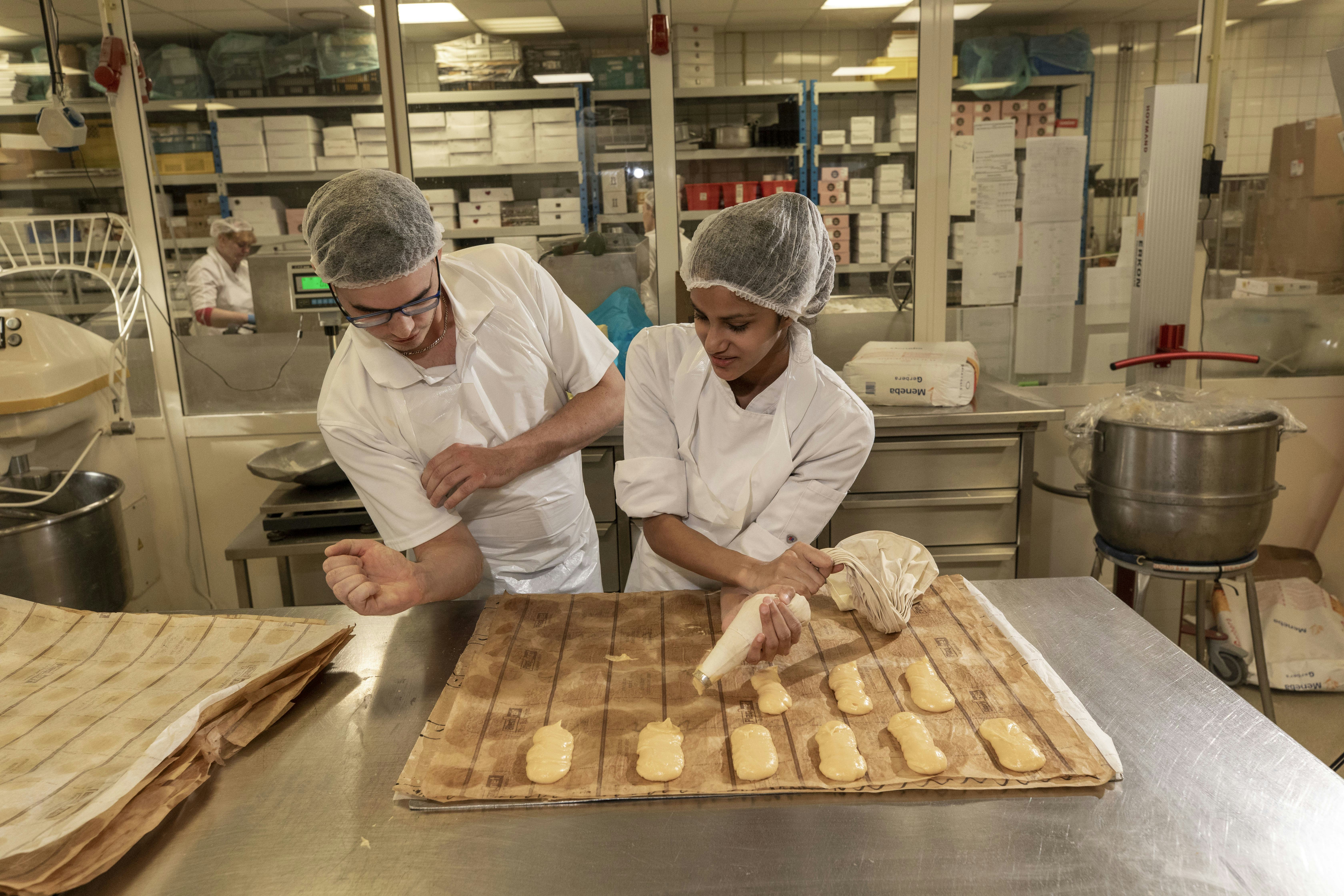 Daniel Boek, banketbakker, ovenist en verantwoordelijk voor boterdeegproducten, begeleidt stagiaire Naomie Naomie.
Foto's: Roel Dijkstra