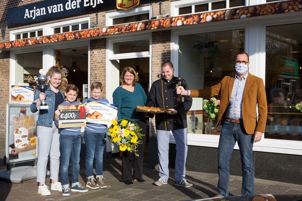 Geert Caniels (rechts) overhandigt de prijs aan Arjan en Bianca van der Eijk en hun kinderen.