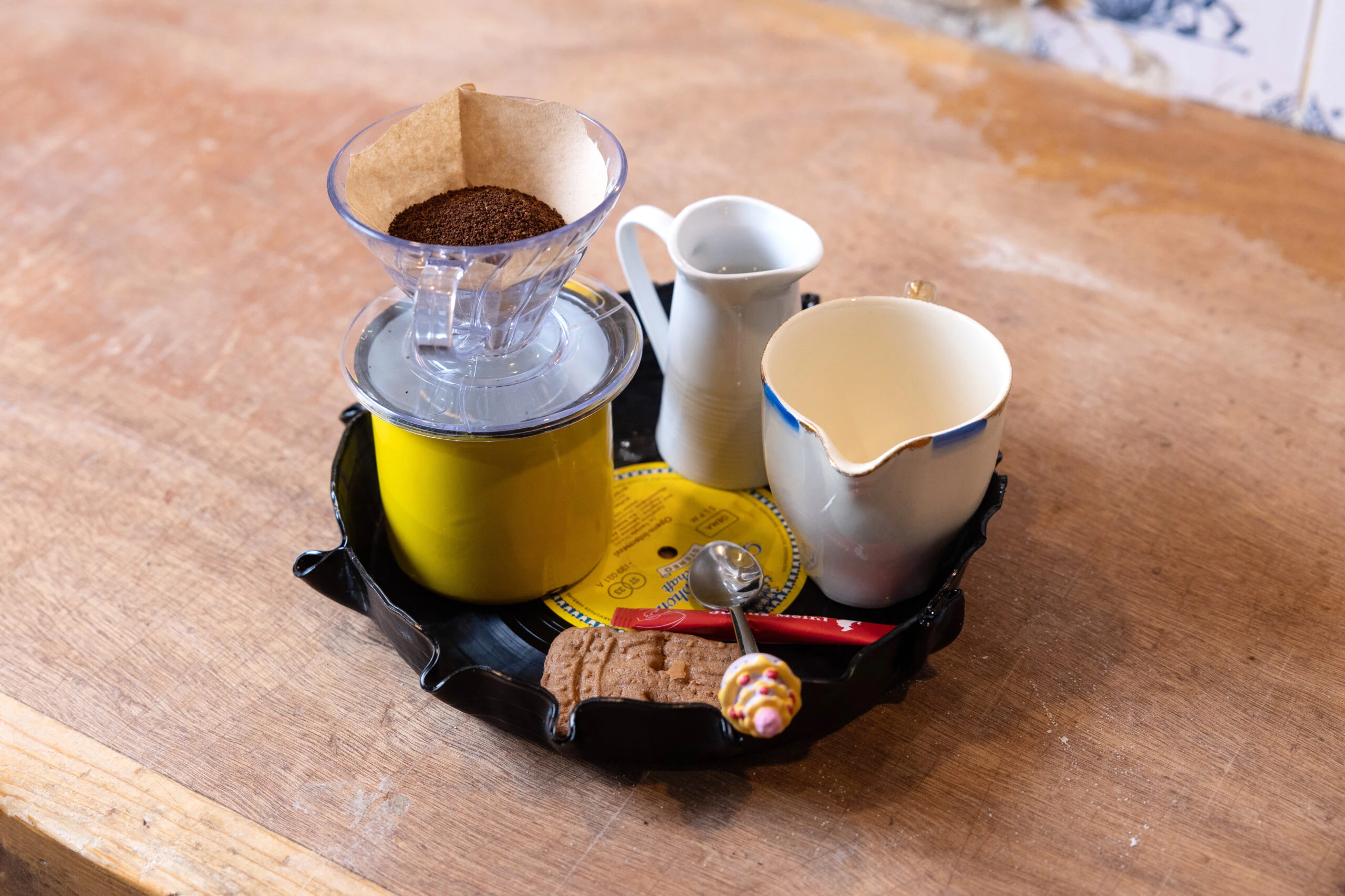 De klant krijgt een plateautje waarop alle attributen staan voor het zelf maken van vegan filterkoffie. Retro.
