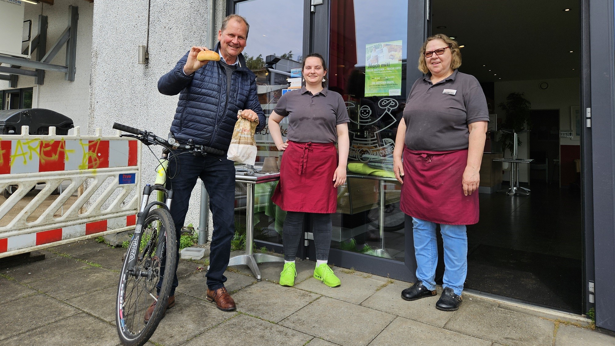 Klant met fiets voor de Kloster-Bäckerei met de verkoopsters Natalia en mevrouw Sögaard.