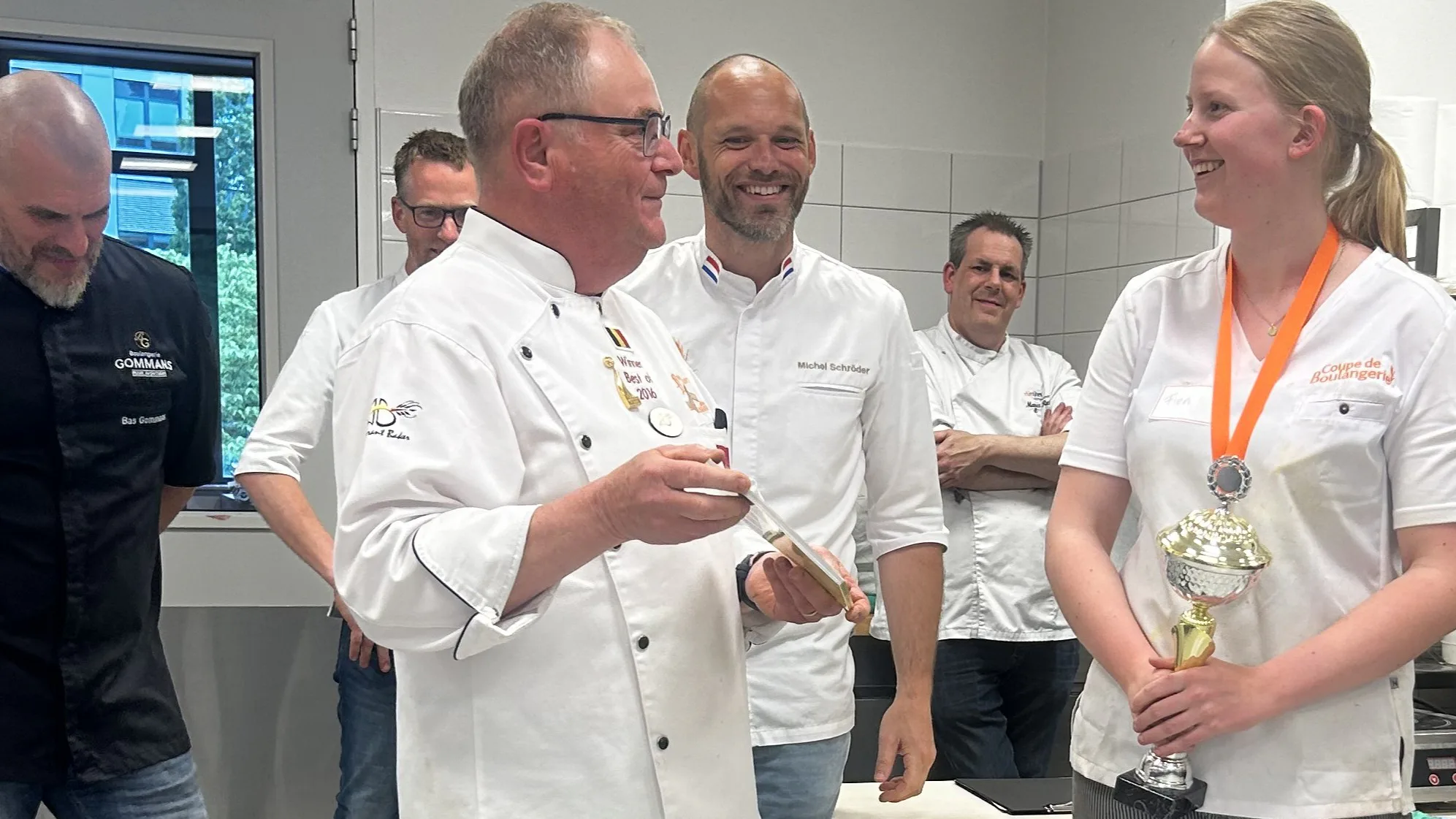 Winnares Fien Kwant wordt lovend toegesproken door jurylid Guido Devillé (wereldkampioen Mondial du Pain 2016), terwijl de andere juryleden meeluisteren.
