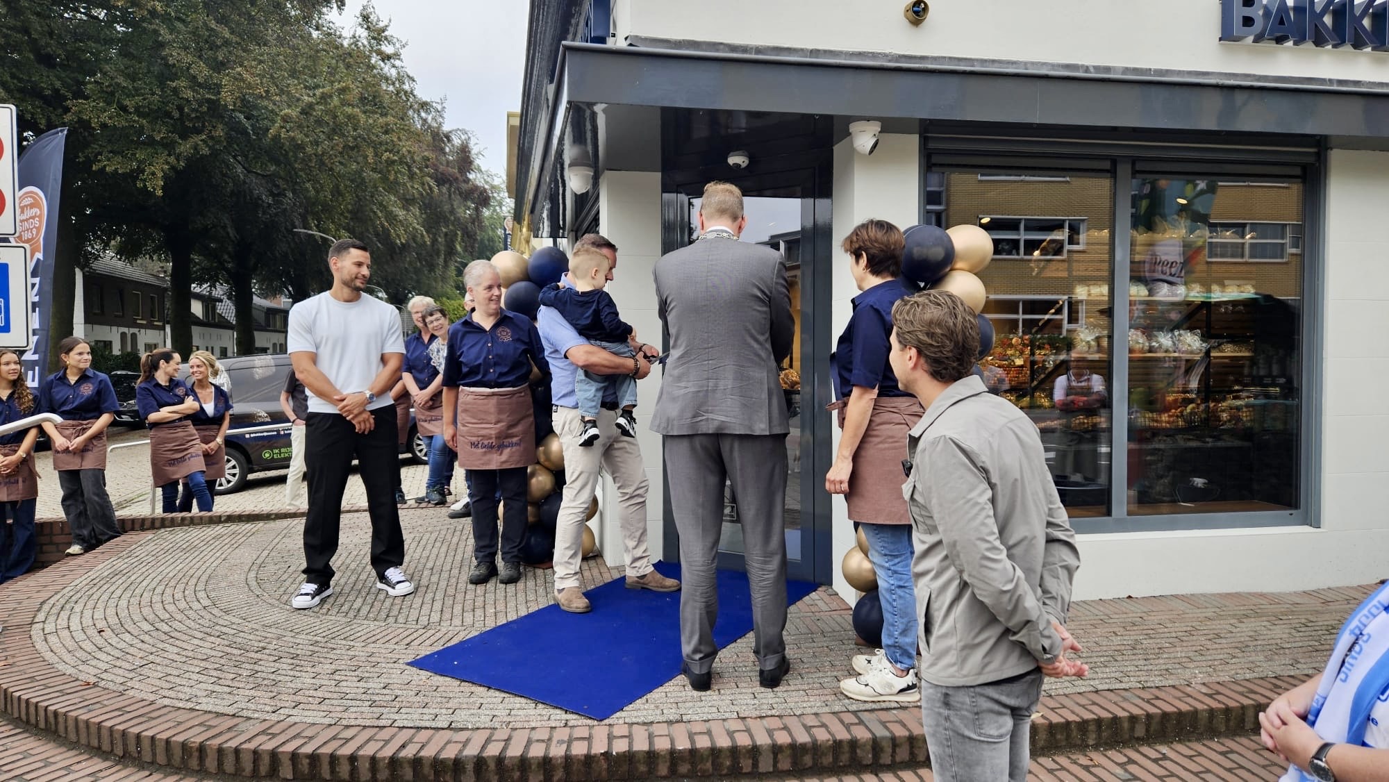 Burgemeester Mark Bouwman van Doetinchem (op de rug gezien) opent samen met drie generaties Koenen de nieuwe winkel.