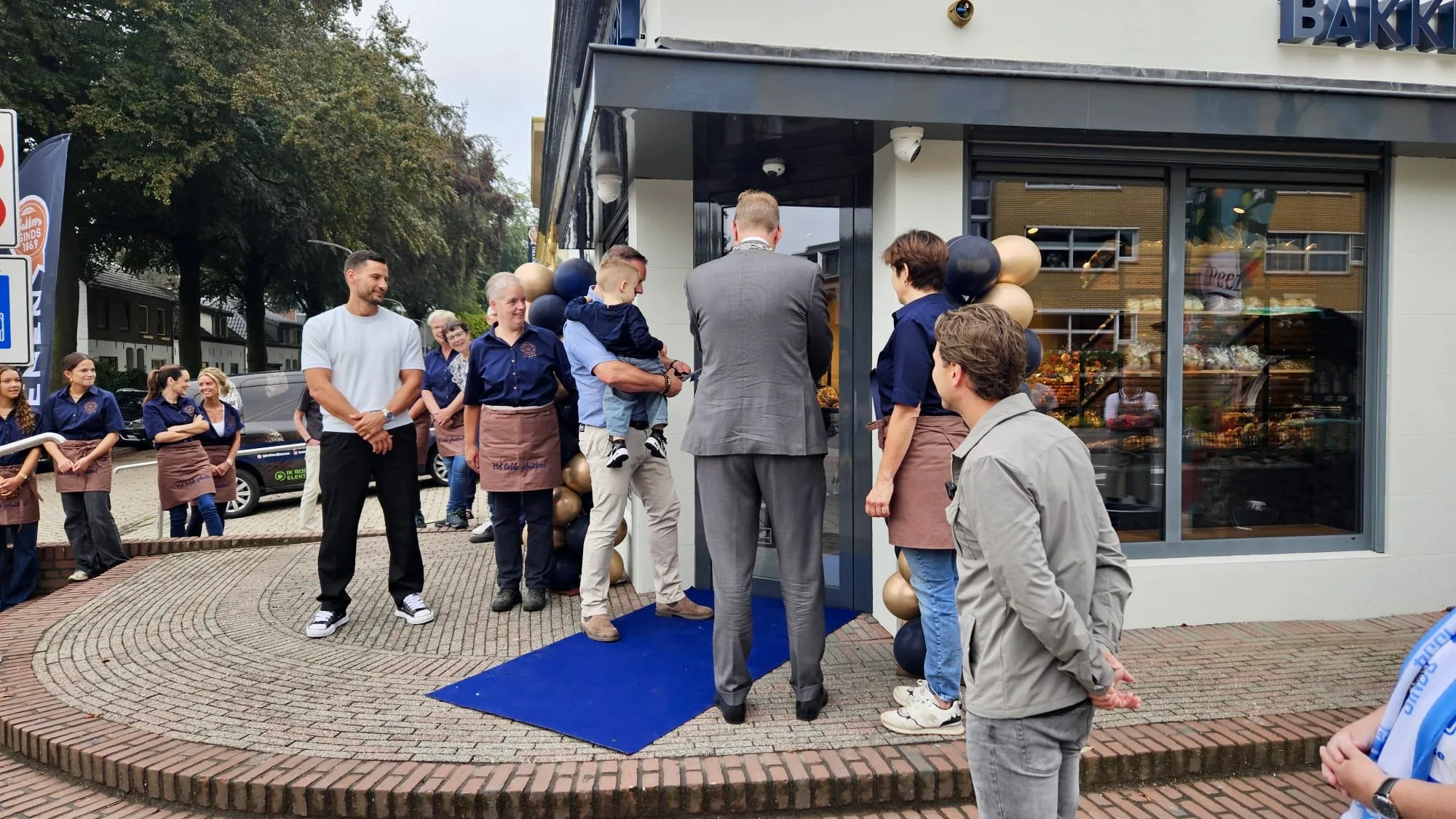 Burgemeester Mark Bouwman van Doetinchem (op de rug gezien) opent samen met drie generaties Koenen de nieuwe winkel.